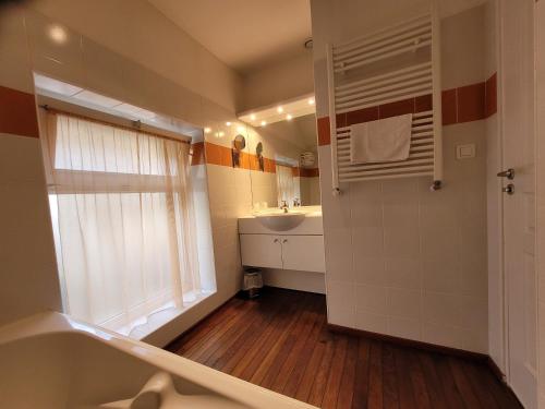 a bathroom with a tub and a sink and a window at Hotel Fouillade in Argentat