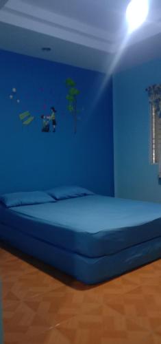 a blue bedroom with a bed with a blue wall at Baan I Mhok Suanphueng in Suan Phung