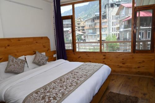 um quarto com uma cama e uma grande janela em Hotel Nirmal Chhaya em Manali