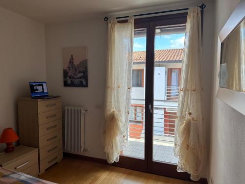 1 dormitorio con puerta corredera de cristal y ventana en Affittacamere La Casa Gialla, en Remanzacco