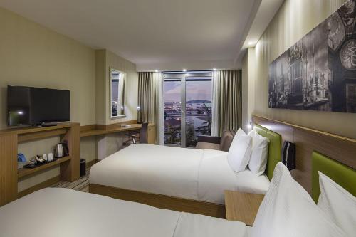 Una habitación de hotel con dos camas y un televisor. en Hampton by Hilton Istanbul Atakoy, en Estambul