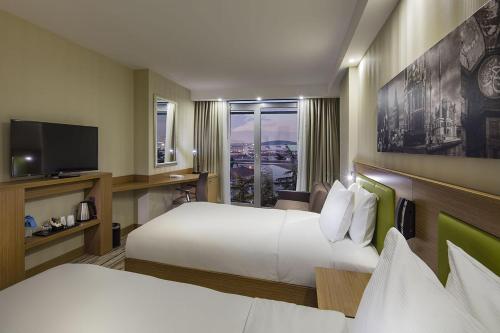 イスタンブールにあるHampton by Hilton Istanbul Atakoyのベッド2台とテレビが備わるホテルルームです。