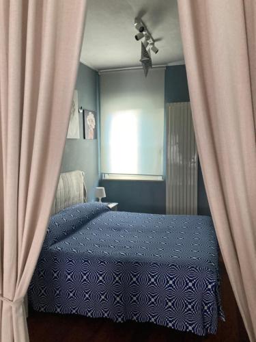 a bedroom with a blue bed with curtains and a window at Piccola Suite in Chieti