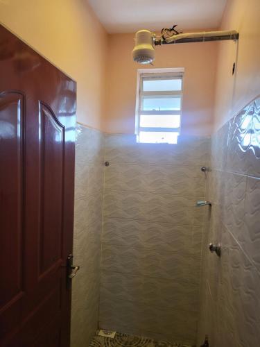 a bathroom with a shower stall and a window at G&G Executive Homes Pipeline Nakuru in Nakuru