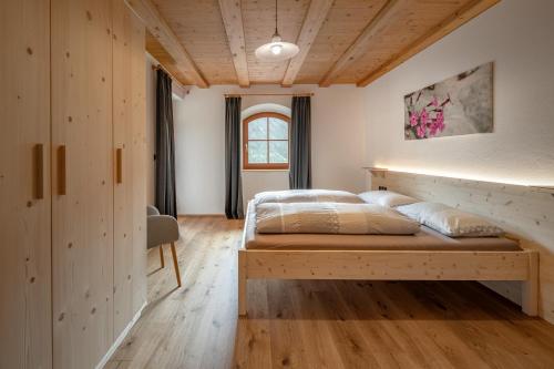 a bedroom with a bed and a wooden ceiling at Veraltenhof Agriturismo B&B in Tires