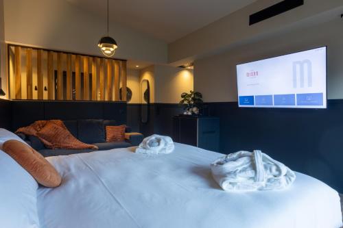 a bedroom with a large white bed and a screen at Miura in Voglans