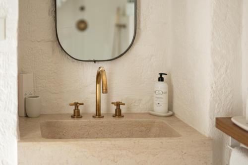 a bathroom sink with a mirror and a bottle of soap at AL PALAZZO La Dimora by Apulia Hospitality in Fasano