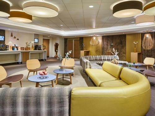 a lobby with couches and tables and a kitchen at Novotel Paris Rueil Malmaison in Rueil-Malmaison