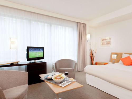 a hotel room with a bed and a television at Novotel Paris Rueil Malmaison in Rueil-Malmaison