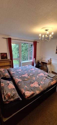 a bedroom with a bed and a desk and a window at Spacious and Serene Stay near Milton Keynes centre in Willen