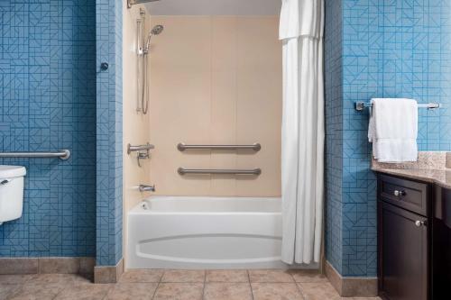 y baño con bañera y ducha con azulejos azules. en Homewood Suites by Hilton Montgomery - Newly Renovated, en Montgomery
