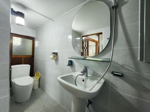 La salle de bains est pourvue d'un lavabo, d'un miroir et de toilettes. dans l'établissement Daepung Stay, à Andong