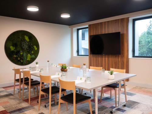 uma sala de conferências com mesas e cadeiras brancas e uma televisão de ecrã plano em ibis Styles Paris Meteor Avenue d'Italie em Paris