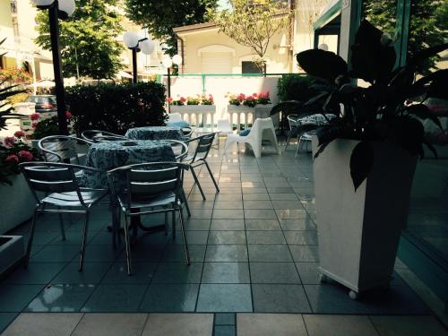 a patio with tables and chairs and a vase with plants at Hotel Sultano in Rimini