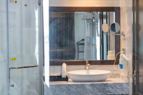 La salle de bains est pourvue d'un lavabo et d'un grand miroir. dans l'établissement Cat Ba Paradise Hotel - Travel Agency, à Cat Ba