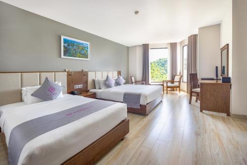 a hotel room with two beds and a desk at Cat Ba Paradise Hotel - Travel Agency in Cat Ba