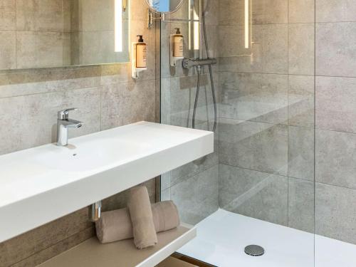 La salle de bains est pourvue d'un lavabo et d'une douche. dans l'établissement Mercure Toulouse Aeroport Blagnac, à Blagnac