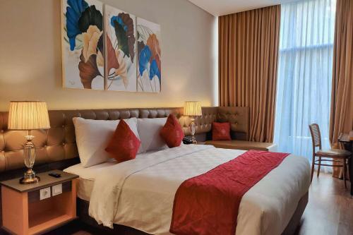 a hotel room with a large bed with red pillows at Ramada by Wyndham Yogyakarta in Yogyakarta