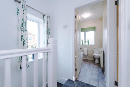 a white bathroom with a toilet and a window at Cosy 3-Bedroom House Near City Centre with Free Parking in York