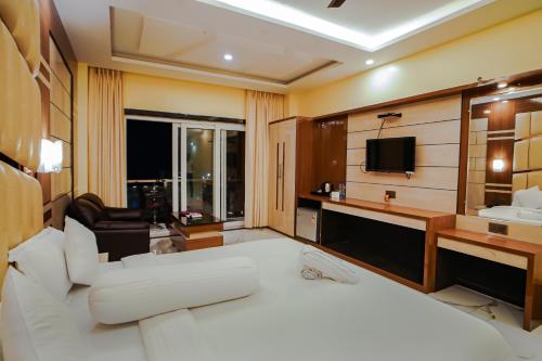 a hotel room with a white bed and a television at Prasant Beach Resort in Mandarmoni