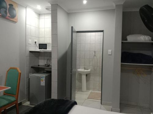 ein Bad mit einer Dusche, einem Waschbecken und einem WC in der Unterkunft Executive Guest House Randfontein in Randfontein