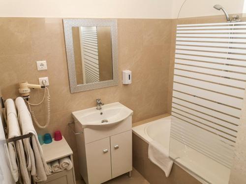 ein Badezimmer mit einem Waschbecken, einer Badewanne und einem Spiegel in der Unterkunft Gold Apartments in Budapest