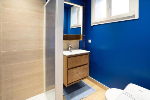 ein Badezimmer mit einem Waschbecken und einer blauen Wand in der Unterkunft L'Exotique - T2 Proche Paris & Bois de Vincennes in Saint-Mandé
