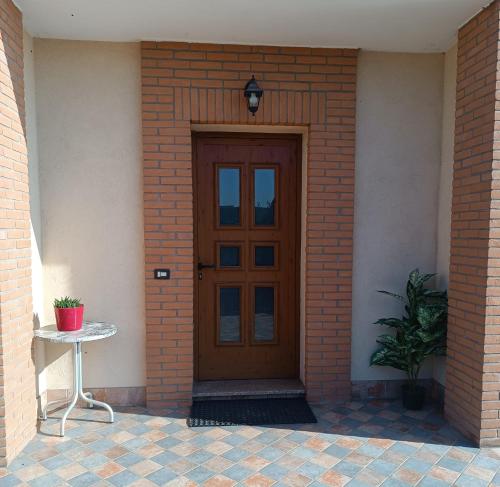 eine Holztür in einem Backsteingebäude mit einem Tisch in der Unterkunft La casetta di Ugo in Grisignano di Zocco