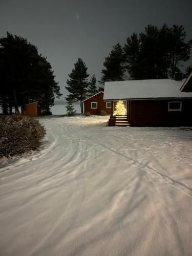 a snow covered road next to a red barn at Lapland Arctic Cabins 