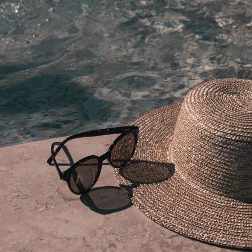 a pair of glasses and a hat next to the water at MORF suites in Casale Marittimo