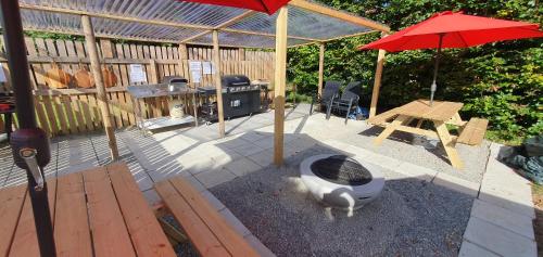 a patio with a grill and a red umbrella at Priory Glamping Pods and Guest accommodation in Killarney