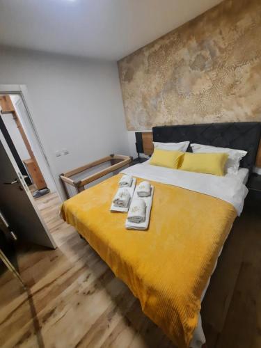 a bedroom with a large bed with a yellow blanket at Apartman Lux-besplatno korišćenje zasebne garaže in Sremska Mitrovica