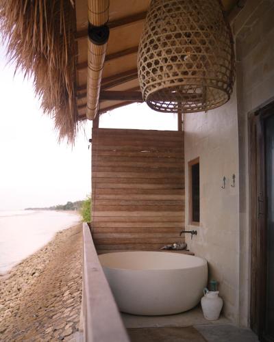 a bathroom with a bath tub on the beach at La Beach Penida in Nusa Penida