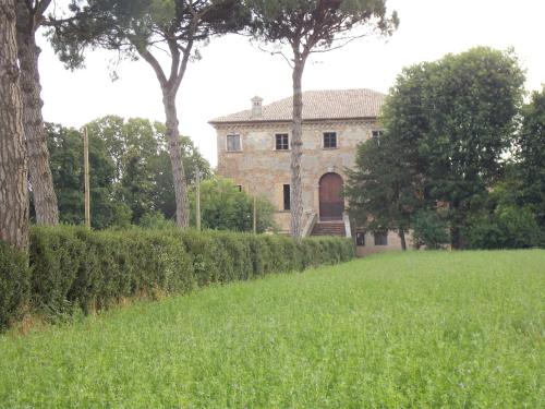 una vecchia casa in un campo con alberi e erba di Bed and Breakfast di Charme La Bonarella a Russi