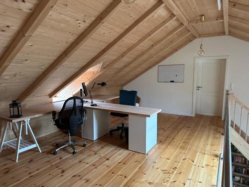 an attic office with a desk in a room with wooden ceilings at Ferienwohnung im Landhaus in Papenburg
