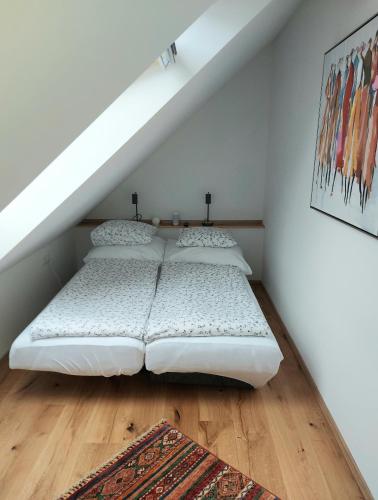 two beds in a room with white walls and wooden floors at Rosenappartement-Deutschkreutz in Deutschkreutz