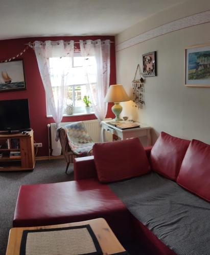 a living room with a red couch and a window at Wohnung am Wanderweg zum Königsstuhl unter Reet in Lohme