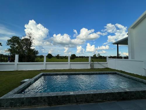 a swimming pool in a yard with a white fence at AKIRA Villa in Buriram