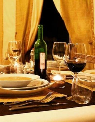 a table with wine glasses and a bottle of wine at Sunset Camp Merzouga in Merzouga