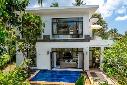 a house with a swimming pool in front of it at Lotus Samui Luxury Beach Villas in Mae Nam