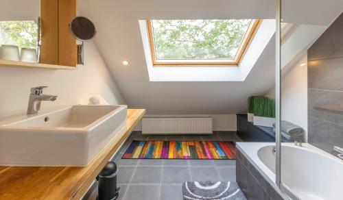 een badkamer met een wastafel, een bad en een raam bij L'Antre d'Eux - Suite avec sauna et jacuzzi 