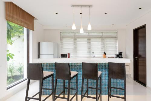 a kitchen with a bar with four stools at Lotus Samui Luxury Beach Villas in Mae Nam