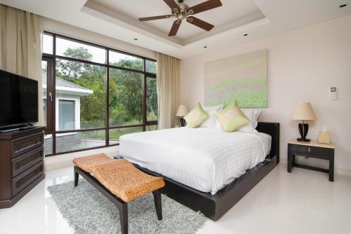 a bedroom with a large bed and a flat screen tv at Lotus Samui Luxury Beach Villas in Mae Nam
