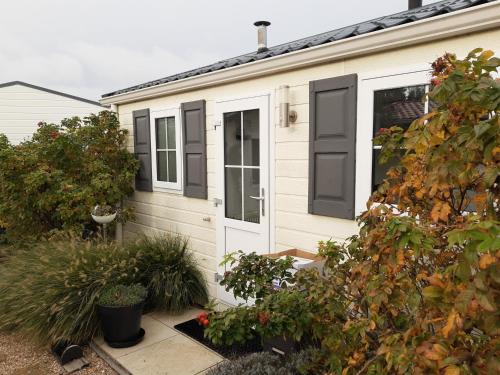 une maison blanche avec volets noirs dans l'établissement GEZELLIGE ZEEMEEUW Bed by the Sea, à Biggekerke