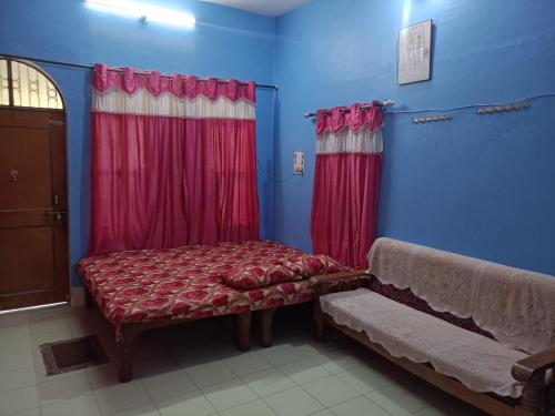 um quarto com uma cama e cortinas vermelhas e um banco em JBP HOME STAY em Prayagraj