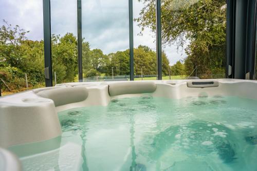 une baignoire jacuzzi dans une chambre avec fenêtres dans l'établissement La Perle Rare - spa, à La Selle-en-Coglès