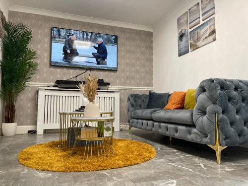 ein Wohnzimmer mit einem Sofa und einem TV in der Unterkunft UPPAMOST LUXURY HOME LONDOn in Dagenham