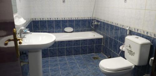 Baño de azulejos azules con aseo y lavamanos en Executive Sharing Bed With Other Male Guests, en Sharjah