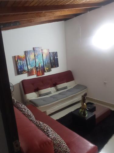 uma sala de estar com um sofá e pinturas na parede em Casa b em Itagüí