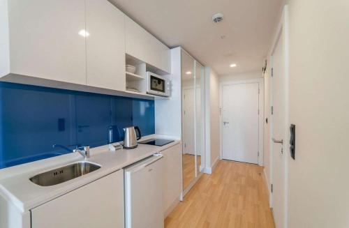 uma cozinha branca com um lavatório e armários azuis em Orbi City Apartments em Batumi